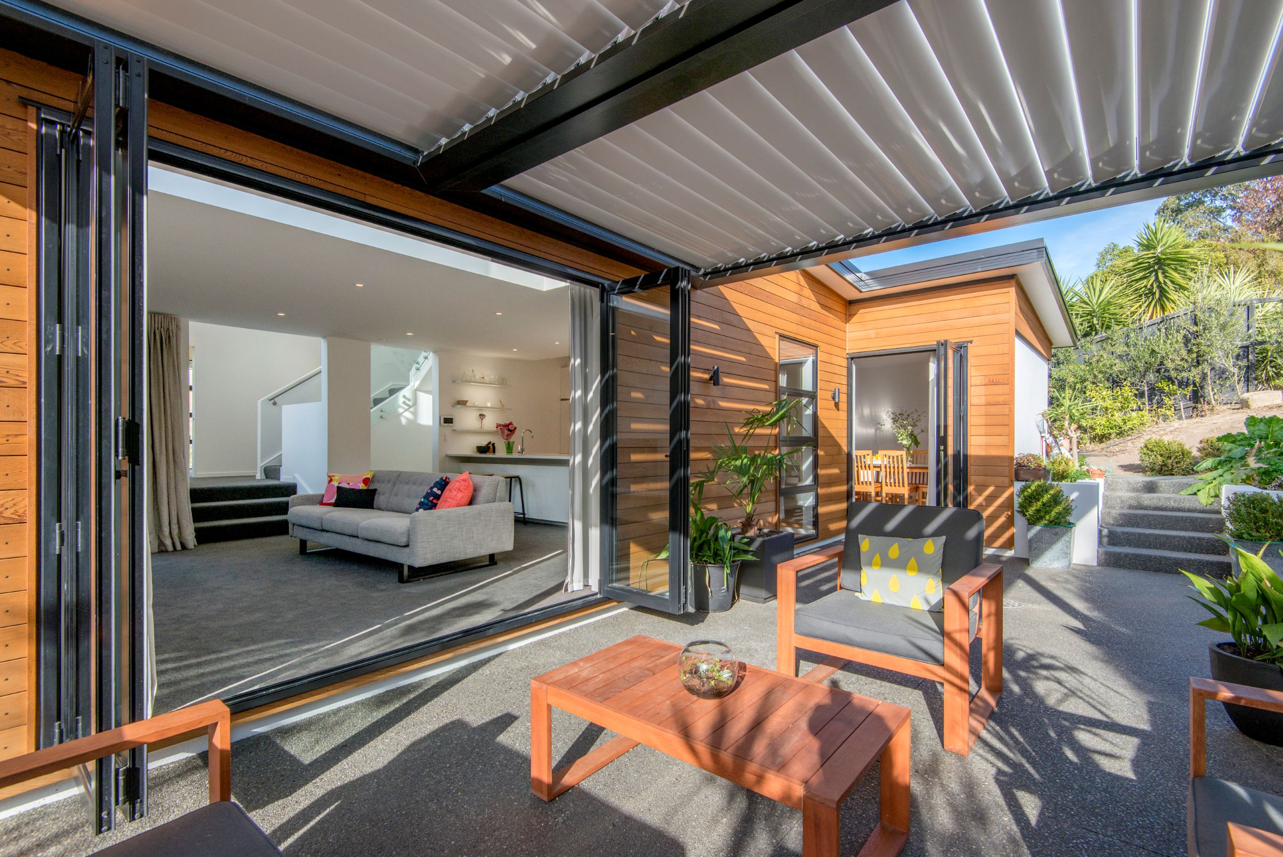 Christchurch-courtyard-exposed concrete-patio-louvre-roof-cedar-weatherboard-living-bifold-doors